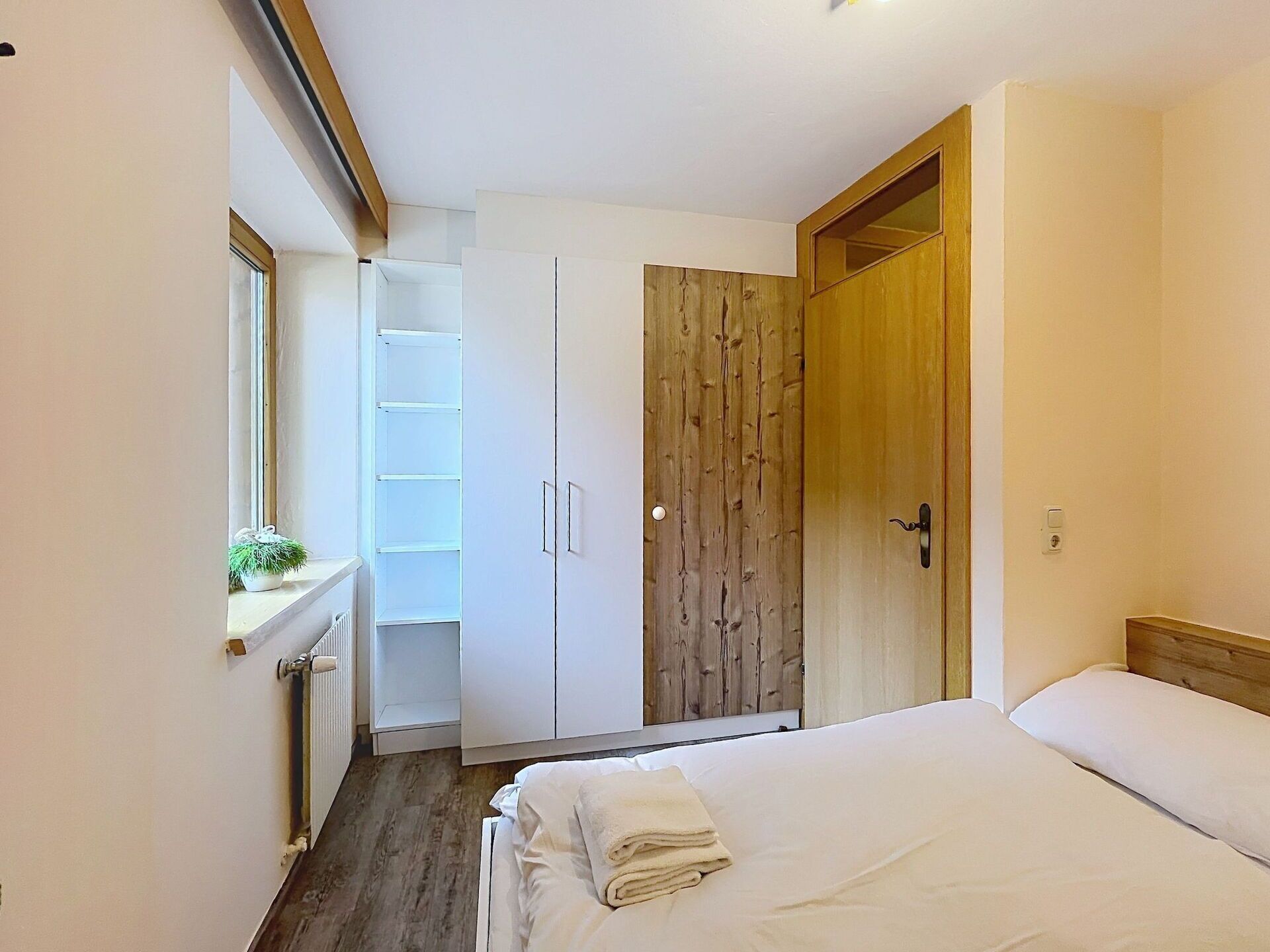 Une chambre  à coucher avec un lit, une armoire en bois et une étagère blanche.