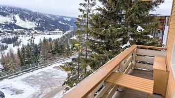 Een balkon met uitzicht op een besneeuwd berglandschap, inclusief een skigebied en een weg.