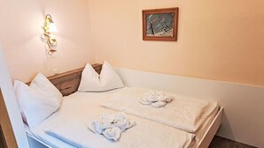 A neatly made bed with white linens and towels, a wooden headboard, a wall-mounted light fixture, and a framed picture on the wall. - Nice apartment for 6 people with WIFI, TV, balcony and pets allowed (St Michael Im Lungau)