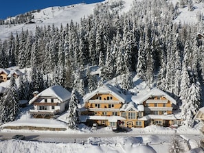 A snow-covered lodge with multiple buildings, surrounded by dense forest and a ski slope in the background. - Nice apartment for 6 guests with WIFI, TV, balcony and pets allowed (St Michael Im Lungau)