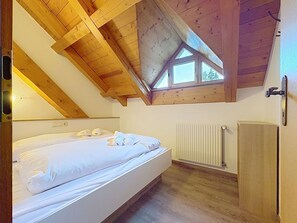 A bedroom with a sloped ceiling, a bed, a radiator, and a window. - Nice apartment for 6 people with WIFI, TV, balcony and pets allowed (St Michael Im Lungau)