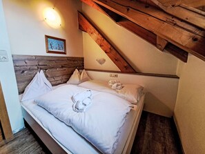 Ein Schlafzimmer mit einem hölzernen Kopfstück, einem Bett mit weißer Bettwäsche, einem gerahmten Bild an der Wand und einer Lampe über dem Bett.
