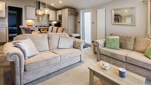 Un salon moderne avec deux canapés, une table basse et une cuisine en arrière-plan.
