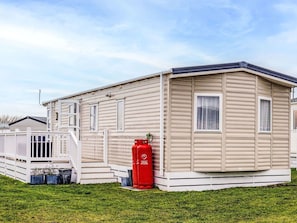 A single-story mobile home with a flat roof, a front porch, and a small attached garage.