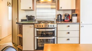 Eine kleine Küche mit Herd, Backofen und Kaffeemaschine.