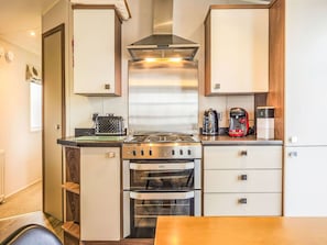 A compact kitchen with a stove, oven, and a coffee maker.
