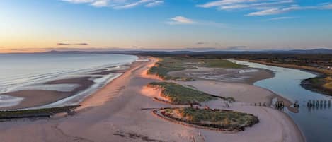 A coastal landscape with a sandy beach, a river, and a small island with vegetation.