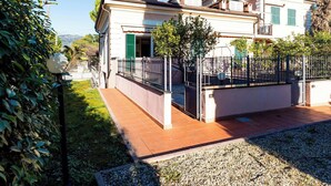Ein zweigeschossiges Haus mit Garten, einem Metallzaun und blauem Himmel.