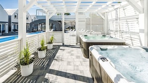 Et overdækket udendørsområde med pool, spa og liggestole.