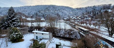 A snow-covered village with houses, a small building, and a train track.