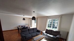 A living room with two sofas, a coffee table, a dining table with chairs, pendant lights, a radiator, and a window with a view. - Spacious house for large family or group - Near Villejuif Metro Line7 (Villejuif)