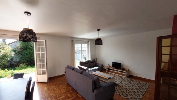 A modern living room with a sofa, TV, and dining area. - Spacious house for large family or group - Near Villejuif Metro Line7 (Villejuif)