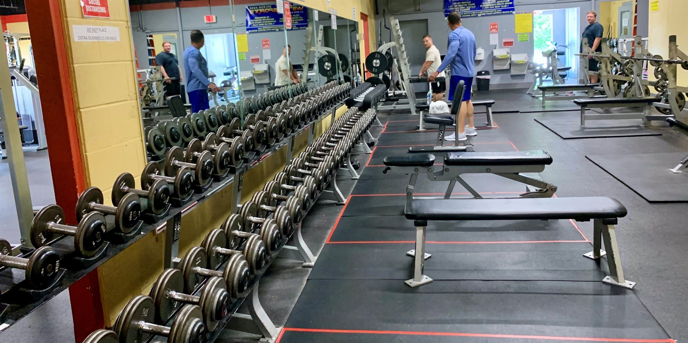 A gym with rows of dumbbells, benches, and weightlifting equipment.