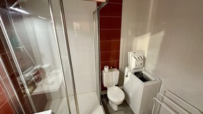 Une petite salle de bain compacte dotée d’une douche à parois de verre, de toilettes et d’un système de filtration de l’eau.