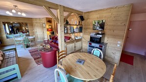 Ein gemütliches Blockhaus-Interieur mit Essbereich, Wohnzimmer mit rotem Sofa und Küchenzeile mit Holzwänden und eingebautem Backofen.