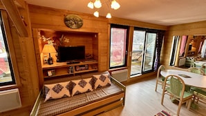 Ein gemütliches Blockhaus-Interieur mit einer hölzernen Bank, einem Fernseher und einem Essbereich.