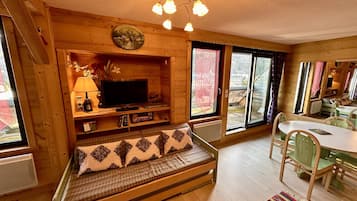 A cozy cabin interior with a wooden bench, a television, and a dining area.