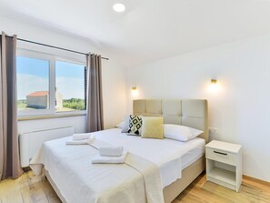 Ein Schlafzimmer mit einem großen Bett, einem Nachttisch und einem Fenster mit Vorhängen.