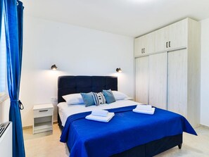 Ein Schlafzimmer mit Bett, Nachttischen, einem Kleiderschrank und einem Vorhang.