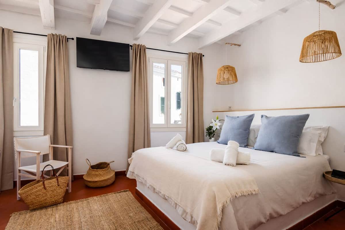 Une chambre à coucher avec un lit, une chaise, une télévision et une fenêtre.