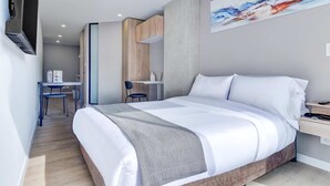 A modern hotel room with a large bed, a desk with a chair, and a painting on the wall. - w Inviting Loft w Balcony in Usaquen (Bogotá)