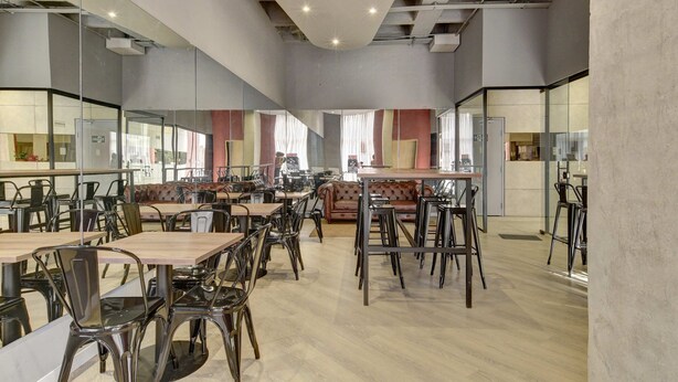 A modern dining area with tables and chairs, a sofa, and a kitchen area in the background. - w Inviting Loft w Balcony in Usaquen (Bogotá)