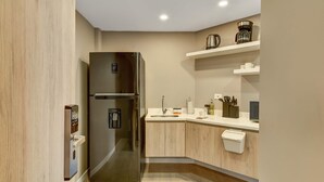 A modern kitchen with a stainless steel refrigerator, wooden cabinets, a sink, and a coffee maker on a shelf. - w Inviting Loft w Balcony in Usaquen (Bogotá)