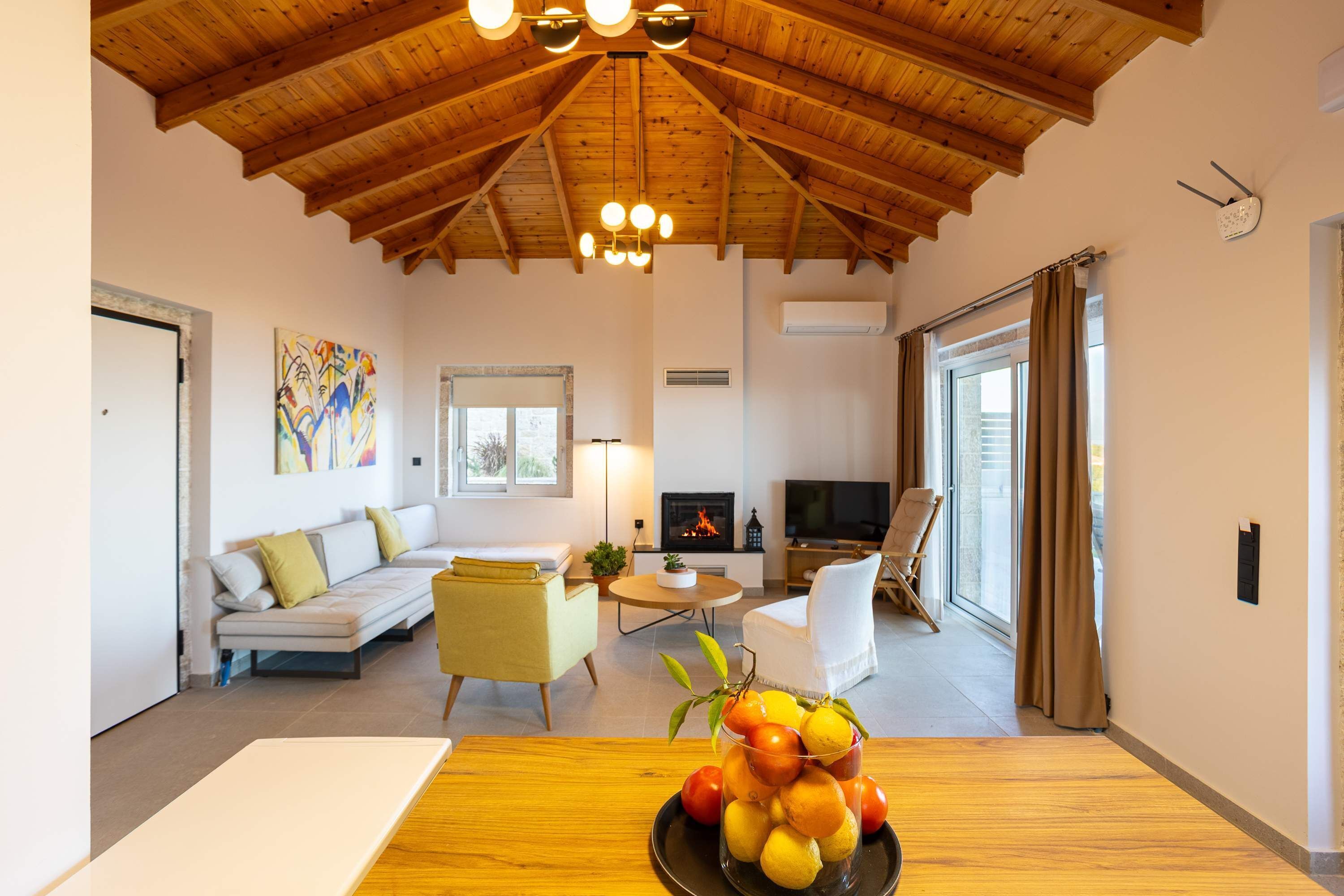 A cozy living room with a wooden ceiling, a sofa, a TV, and a fireplace.