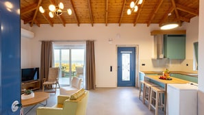 Ein modernes Wohnzimmer mit Fernseher, Sitzgelegenheiten und einem großen Fenster.