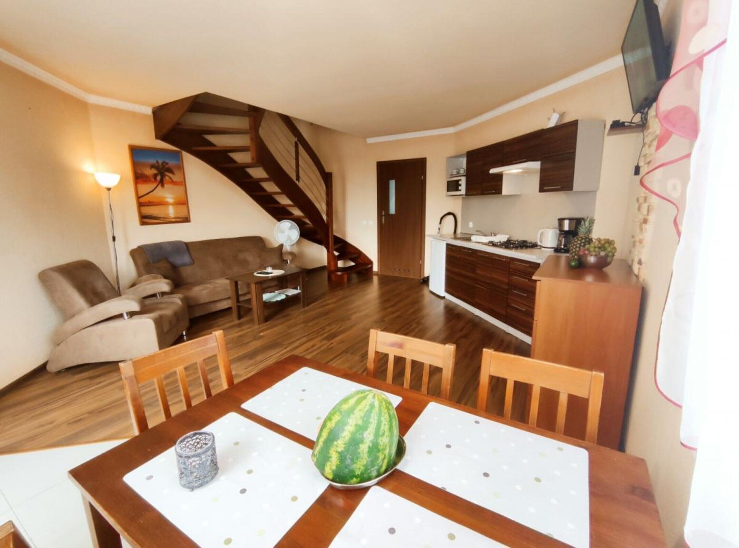 A compact living space with a dining area, kitchenette, and a staircase.