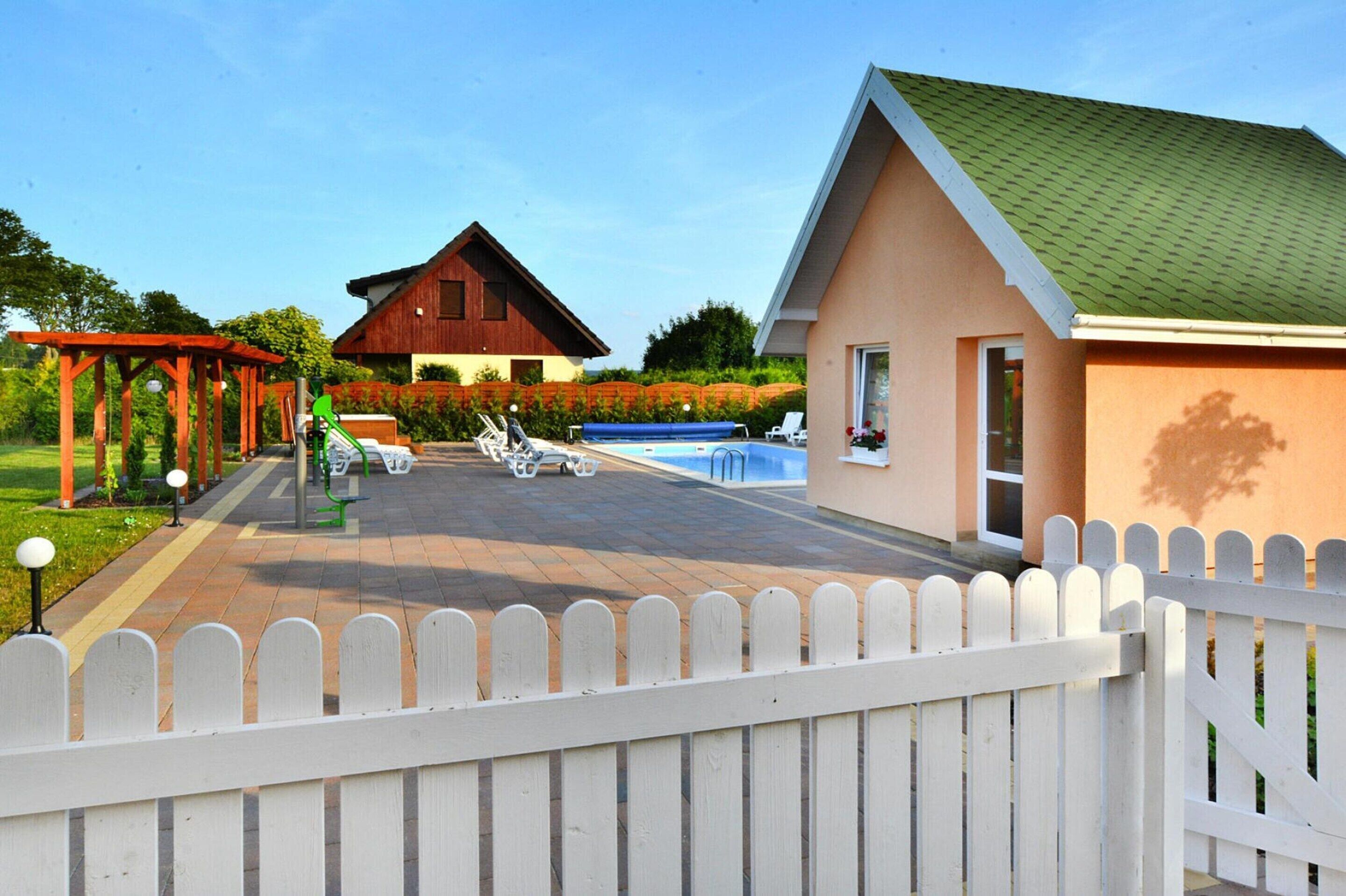 A residential property with a swimming pool, outdoor seating, and a wooden deck.