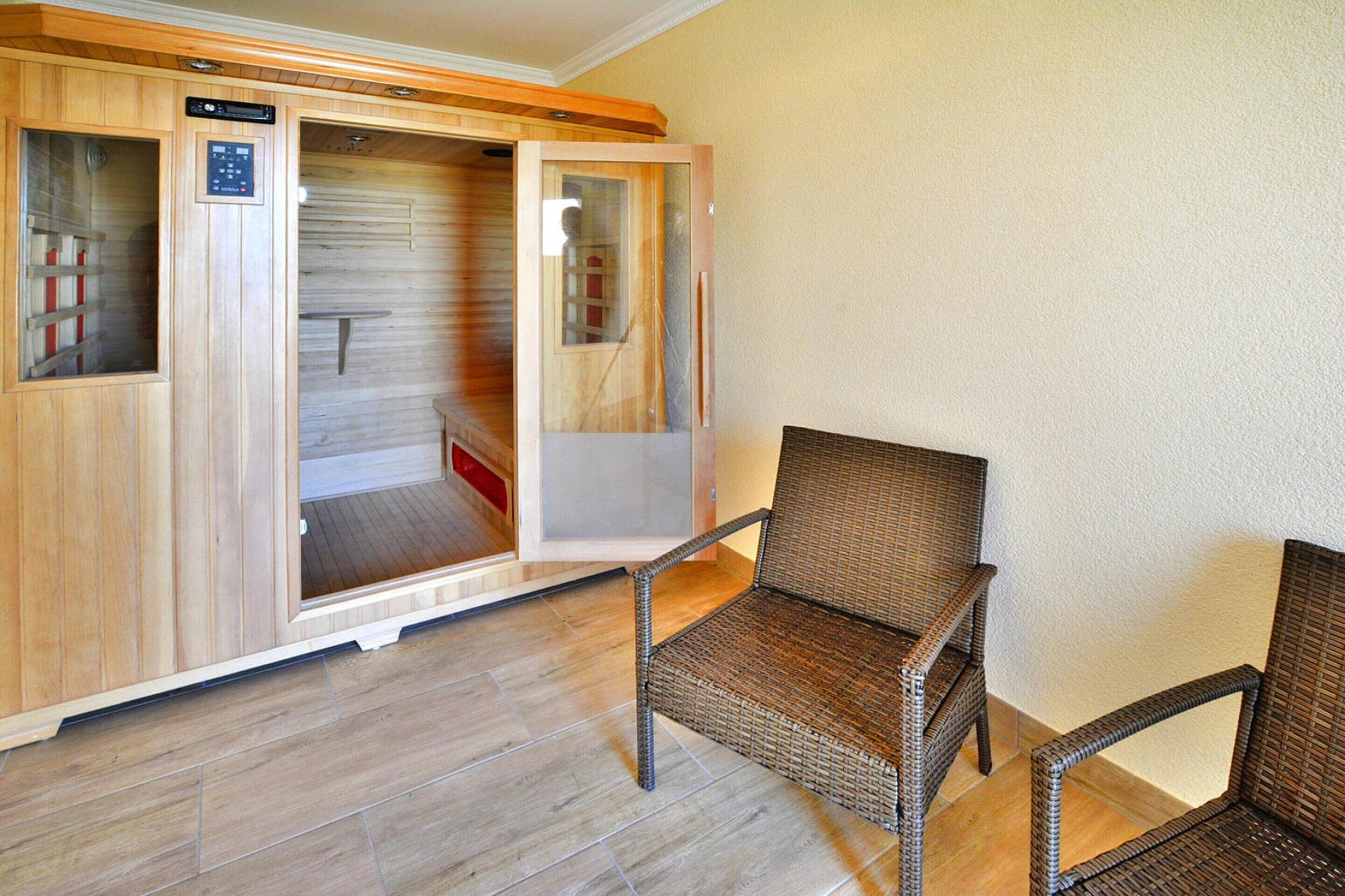 A sauna room with a wooden bench and a control panel.
