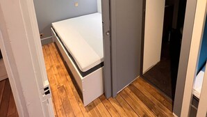Une chambre compacte avec un lit simple, un plancher en bois et une armoire intégrée.