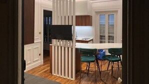 Une cuisine moderne avec un plancher en bois, un îlot central et deux chaises vertes.