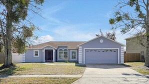 A single-story house with a garage, a front door, and a small porch. - Minutes to Disney | Cozy 3BR Florida Escape (Kissimmee)