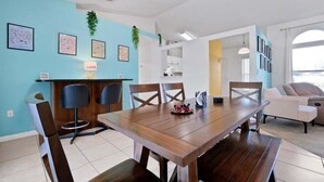 A dining area with a wooden table, four chairs, and a small bar area with stools. - Minutes to Disney | Cozy 3BR Florida Escape (Kissimmee)