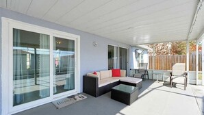 A covered patio area with a sofa, a coffee table, and a dining table. - Minutes to Disney | Cozy 3BR Florida Escape (Kissimmee)