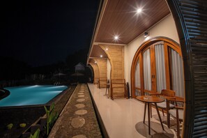 A poolside area with a pool, wooden deck, and seating arrangements.