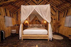 Una habitación con cama con dosel, paredes de madera y techo inclinado.
