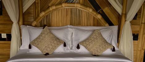 A bed with a canopy, white bedding, and a 'WELCOME HOME' sign.