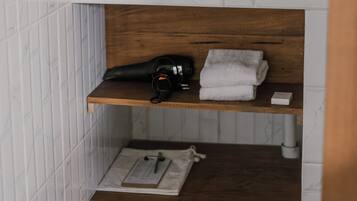 A bathroom with a white sink, wooden shelves, a towel rack, and a mirror.