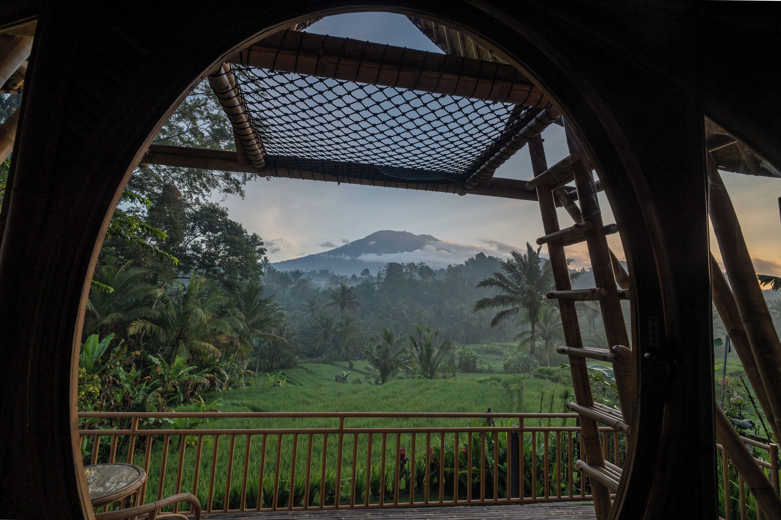 Un balcón de madera con vistas a una montaña y abundante vegetación.