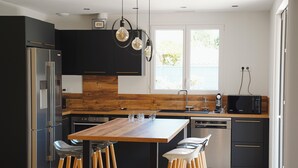 A modern kitchen with a central island, bar stools, a microwave, and a dishwasher.