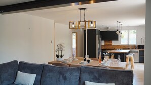 A modern living room with a sofa, dining table, and kitchen in the background.