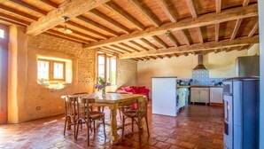 Una cocina rústica con vigas de madera a la vista, una pared de piedra y un suelo de baldosas.