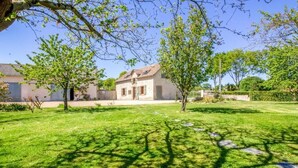 Una casa con un césped cuidado y algunos árboles.