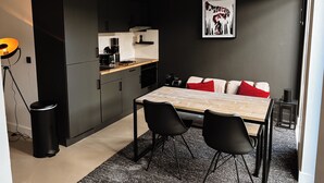 Een moderne keuken met donkere kastjes, een houten aanrechtblad en een eethoek met een tafel en stoelen.