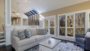 A spacious living room with a large window, a sofa, a coffee table, and a patterned rug. - 1981 St Andrews: Pet Friendly 2 Beds, 2 Baths, Palmetto Dunes villa (Hilton Head Island)