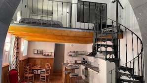 A spacious loft-style apartment with a kitchen, dining area, and a black spiral staircase. - La Chapelle - Le Mont Dore 2 Pers (Mont-Dore)