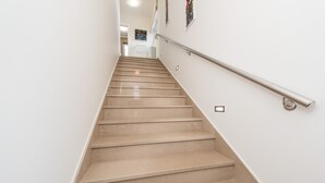 Een trap met een leuning, die leidt naar een kamer met een witte muur en een deur aan de bovenkant.